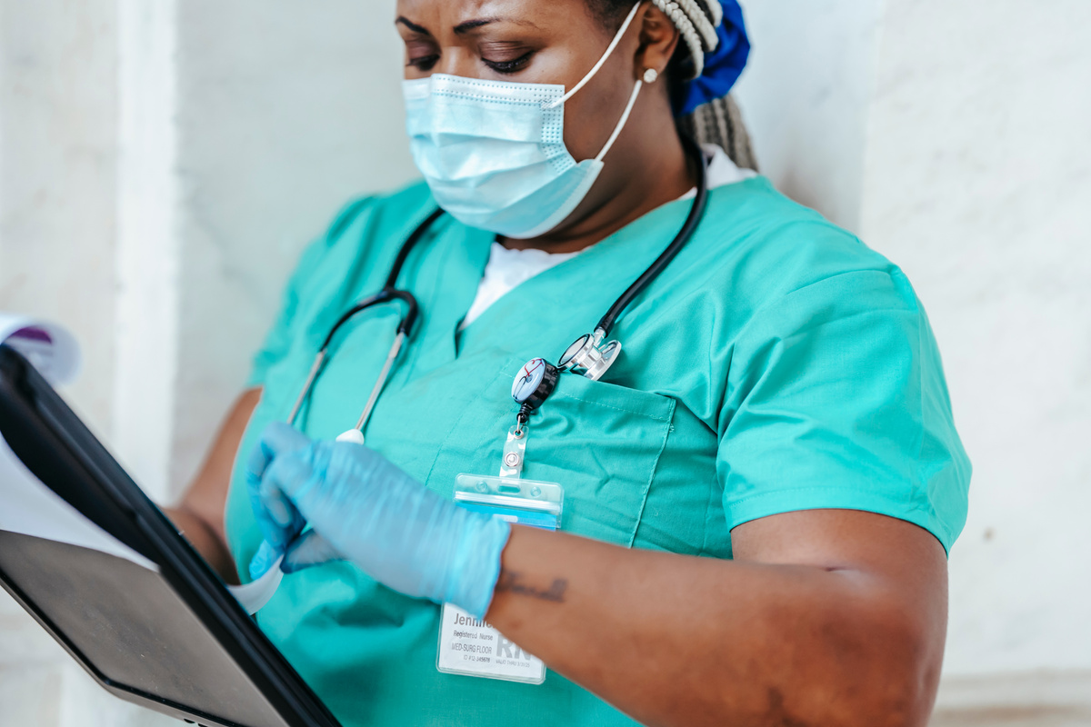 Crop nurse in mask and gloves with papers